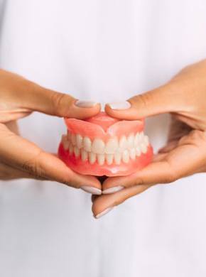 a person holding a pair of new dentures
