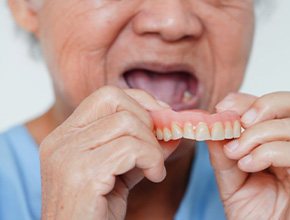 a person removing their dentures