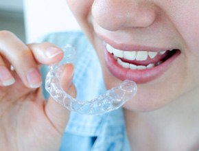 Nose-to-neck view of someone holding Invisalign up close to their mouth