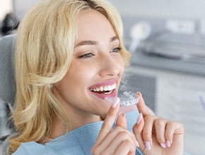 Woman in dental chair about to insert Invisalign
