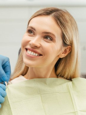 Blonde woman sitting in dental chair and smiling at dentist