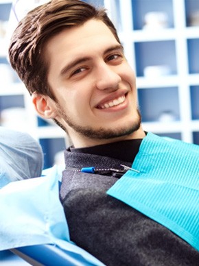 Male dental patient sitting in chair and smiling