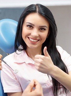 Woman in dental chair giving thumbs up