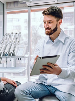 Dentist and patient smiling while reviewing paperwork