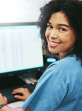 smiling dental team member sitting at computer