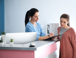 patient speaking with member of dental office front desk team