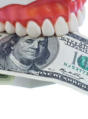A model of a mouth holding a $100 bill.