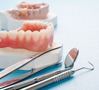 full dentures sitting next to dental tools