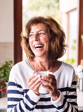 person holding a cup of coffee and smiling