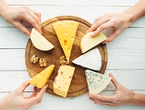 Hands taking cheese off of a circular dish