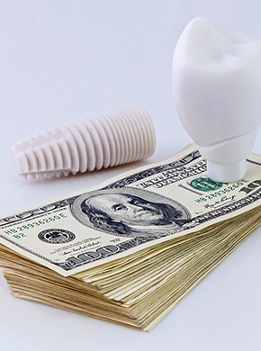 Stack of money with dental implant in Lisle, IL