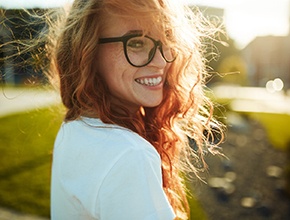 Smiling woman with glasses and dental implant in Lisle, IL