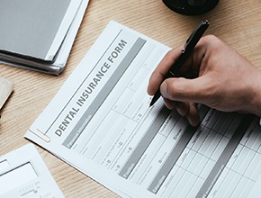 Filling out dental insurance form on crowded desk