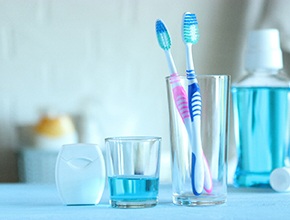 Toothbrush in glass, mouth rinse, and floss