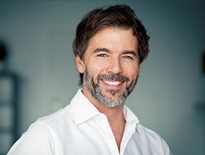 smiling older man wearing a white dress shirt 