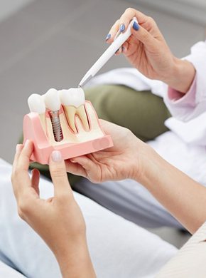 dentist showing a dental implant model to a patient 