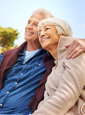 happy elderly couple sitting on a park bench