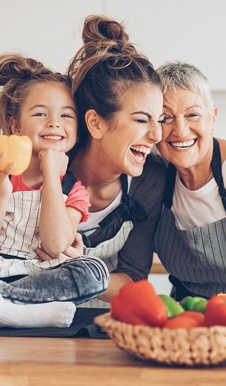 Mother daughter and granddaughter laughing together in front of a table with food