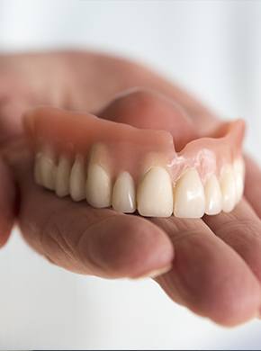 Hand holding full dentures