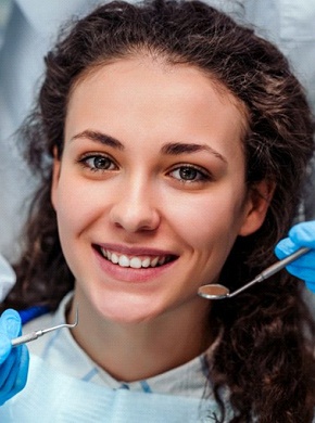 woman with curly hair smiling before root canal therapy in Manchester