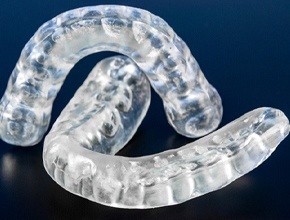 Two occlusal splints for TMD arranged against dark background