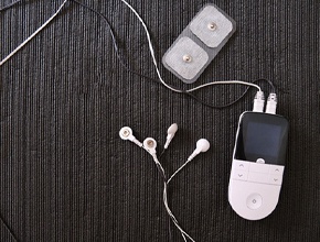 Small, white TENS machine arranged against dark background