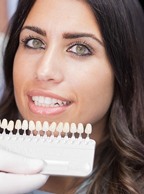 A dentist comparing veneer shades with a patient’s current smile.