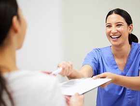 Dental team member handing clipboard to patient
