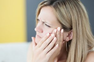 Woman with jaw pain, wondering about TMD causes