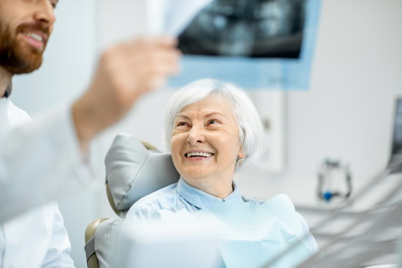 elderly patient smiling while speaking with cosmetic dentist