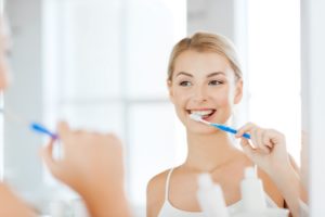 Woman looking in mirror and brushing her teeth